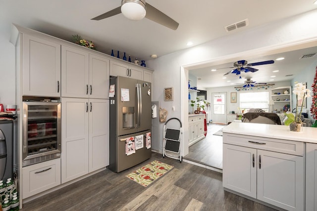 kitchen with dark wood-type flooring, stainless steel fridge with ice dispenser, ceiling fan, beverage cooler, and white cabinets