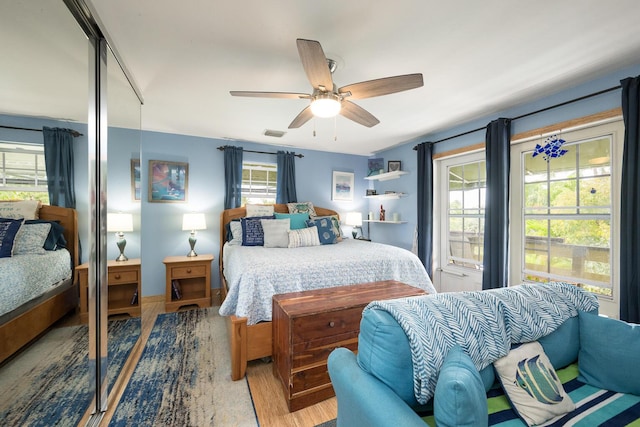 bedroom with multiple windows, hardwood / wood-style flooring, and ceiling fan