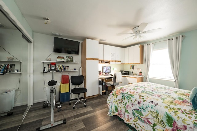 bedroom with dark hardwood / wood-style flooring, built in desk, a closet, and ceiling fan