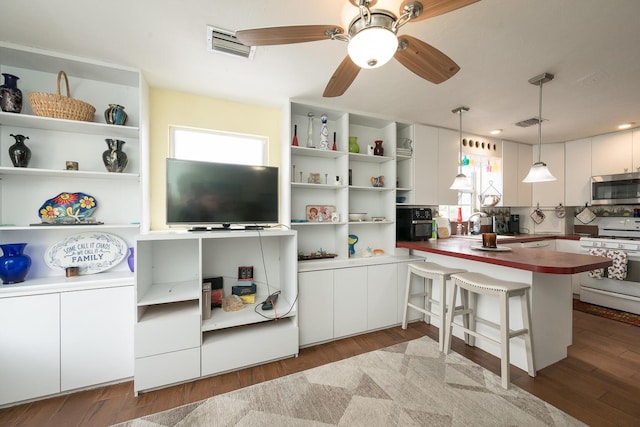 kitchen with white cabinetry, pendant lighting, a kitchen breakfast bar, and white stove