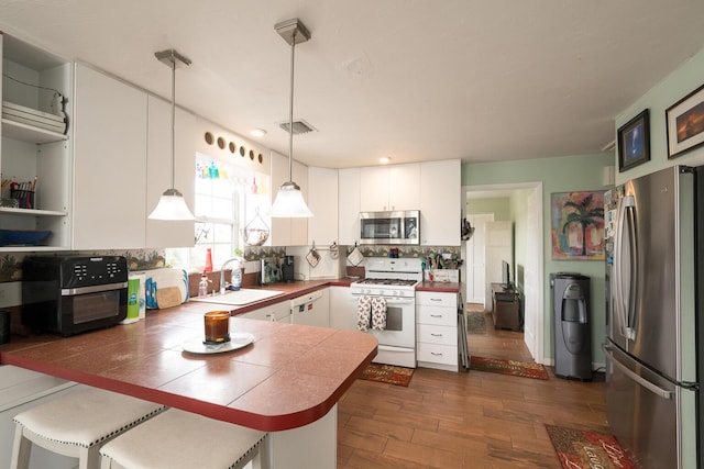 kitchen with sink, a breakfast bar, hanging light fixtures, stainless steel appliances, and kitchen peninsula