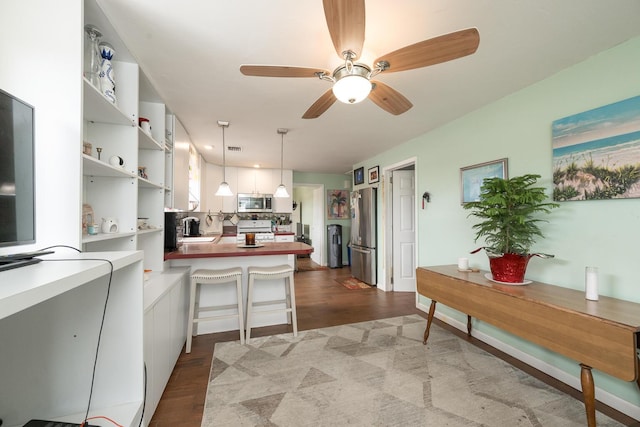 kitchen with sink, white cabinetry, kitchen peninsula, pendant lighting, and stainless steel appliances