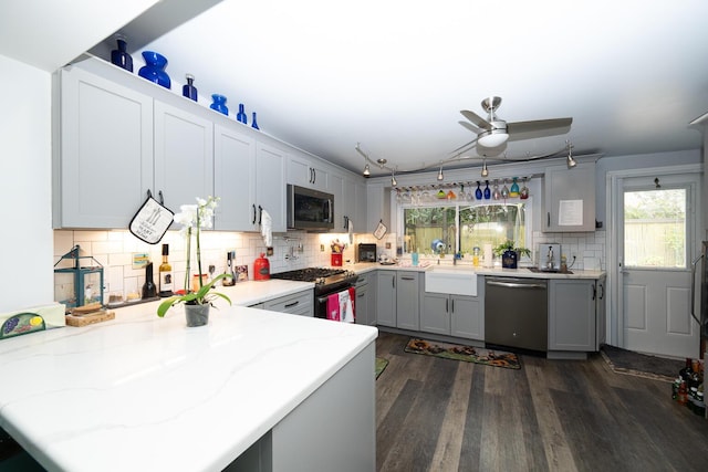 kitchen featuring appliances with stainless steel finishes, tasteful backsplash, sink, dark hardwood / wood-style flooring, and kitchen peninsula