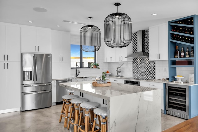 kitchen with a kitchen island, pendant lighting, stainless steel appliances, beverage cooler, and wall chimney range hood