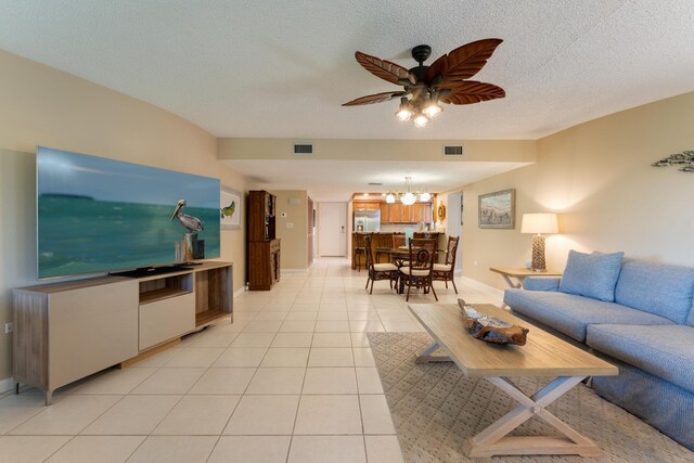 tiled living room with ceiling fan with notable chandelier and a textured ceiling