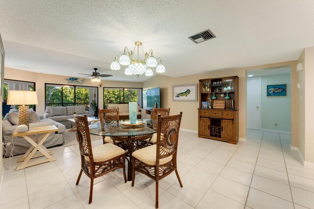 tiled dining area with ceiling fan with notable chandelier and a textured ceiling