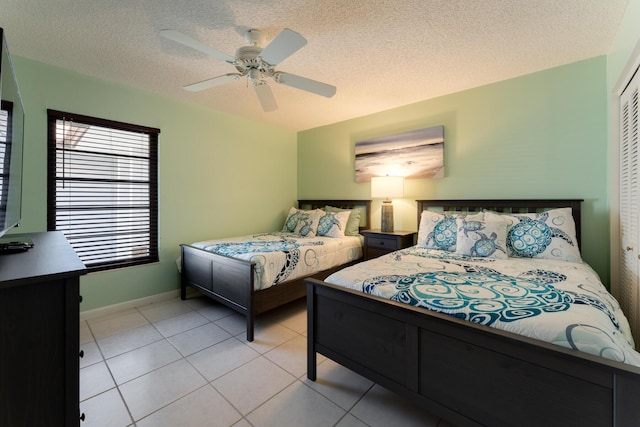 tiled bedroom with ceiling fan, a closet, and a textured ceiling