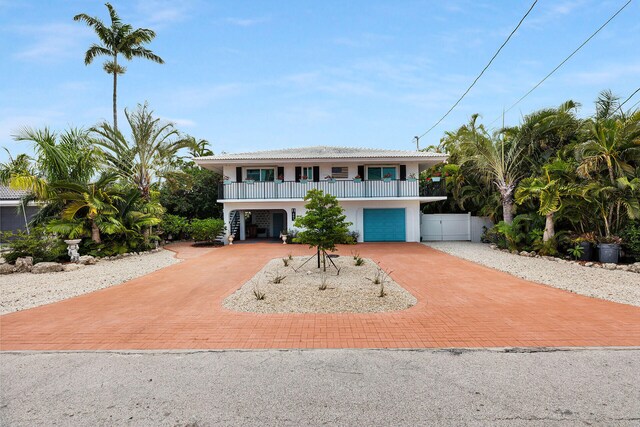 661 12th St, Key Colony, FL 33051 - coastal home featuring decorative driveway, stucco siding, stairs, an attached garage, and a porch