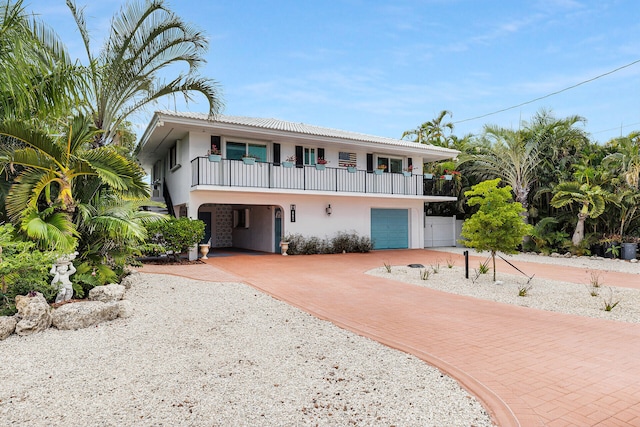 661 12th St, Key Colony, FL 33051 - view of front of home featuring stucco siding, a balcony, decorative driveway, and a carport
