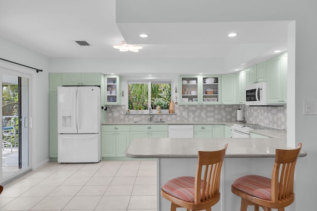 661 12th St, Key Colony, FL 33051 - kitchen with white appliances, a peninsula, light countertops, a kitchen bar, and decorative backsplash
