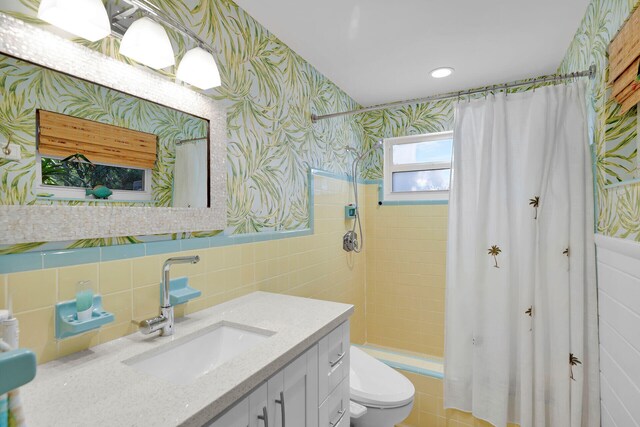 bathroom with vanity, toilet, tile walls, and a shower with shower curtain