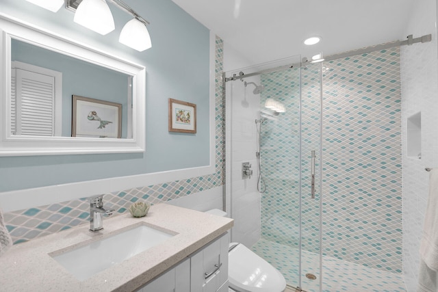 bathroom with vanity, a shower with door, tile walls, and toilet