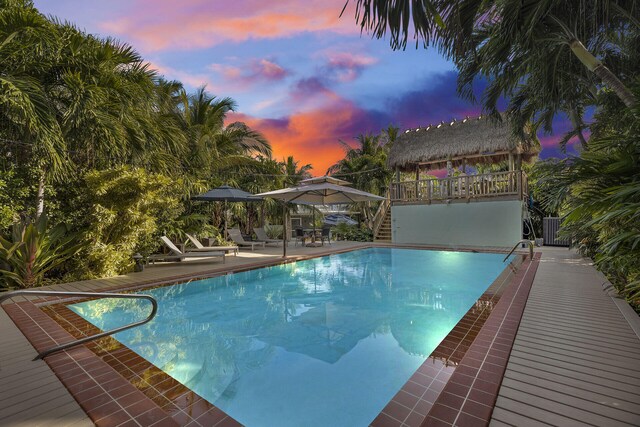 pool at dusk with central AC unit, a gazebo, and a patio