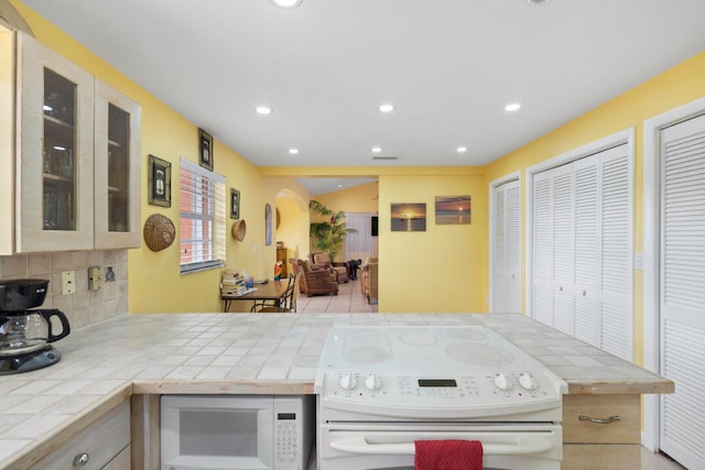 kitchen with backsplash, white appliances, and tile countertops