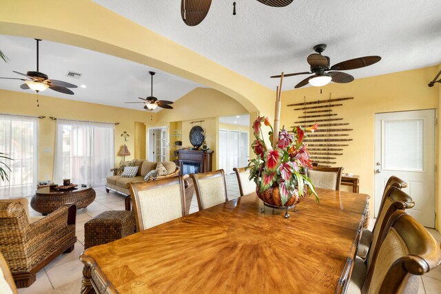 dining room featuring lofted ceiling, ceiling fan, a textured ceiling, and light tile patterned flooring