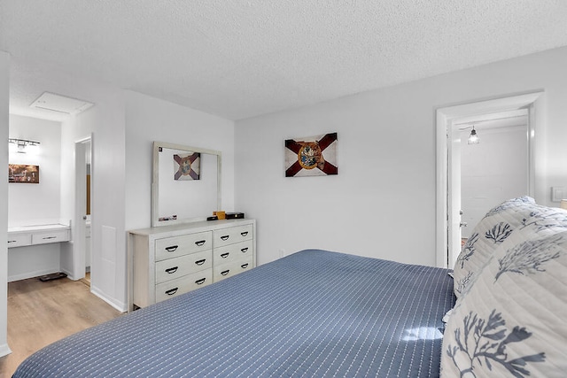 bedroom featuring built in desk, a textured ceiling, and light wood-type flooring