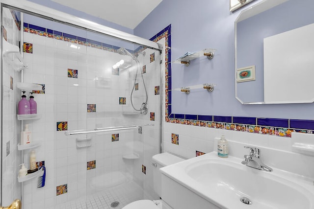 bathroom featuring toilet, sink, a shower with door, and tile walls