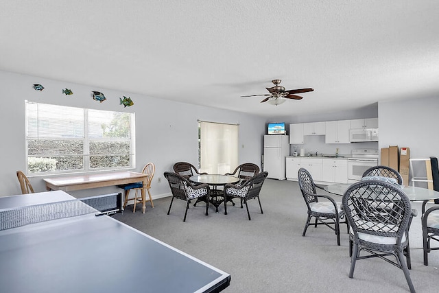 dining area featuring ceiling fan, light carpet, and a textured ceiling