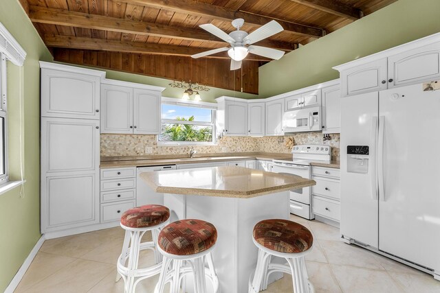 kitchen with white cabinets, a kitchen breakfast bar, decorative backsplash, a center island, and white appliances