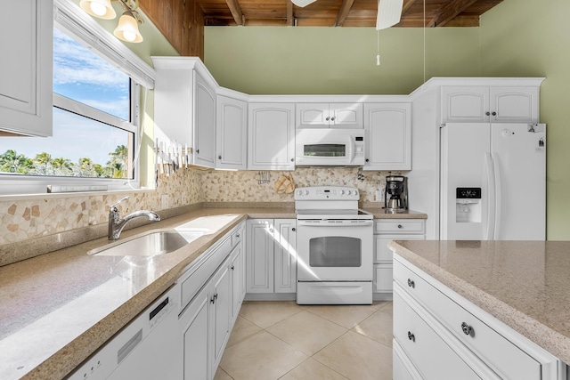 kitchen with light stone countertops, sink, white cabinets, and white appliances