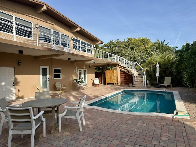 outdoor pool with outdoor dining area, a patio, and stairway