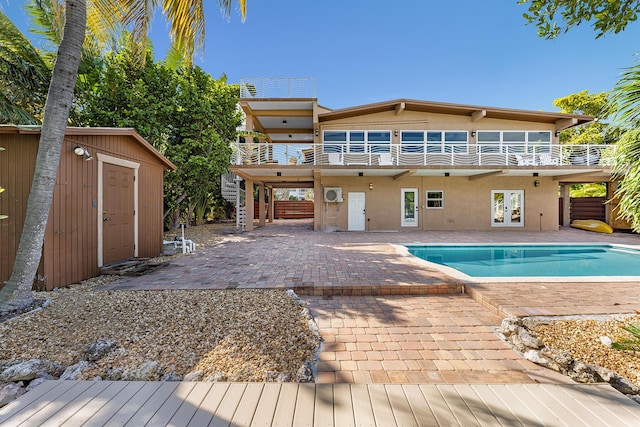 rear view of house featuring a balcony, a pool side deck, a shed, a patio area, and french doors