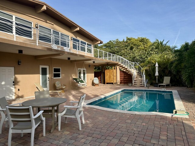 outdoor pool with stairs, outdoor dining area, and a patio area