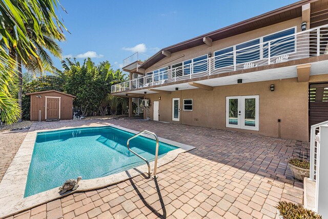 view of swimming pool featuring french doors, a storage unit, and a patio