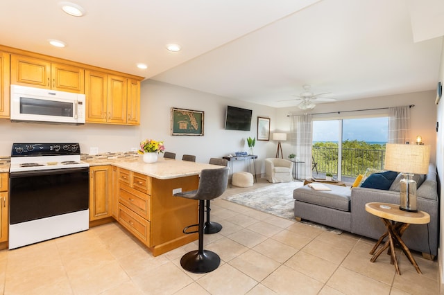 kitchen featuring light tile patterned floors, a breakfast bar, electric range oven, light stone countertops, and kitchen peninsula