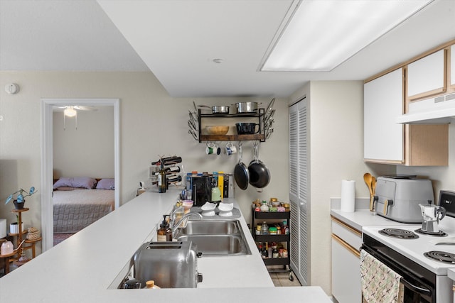 3635 Seaside Dr Unit 314, Key West, FL 33040 - kitchen with light countertops, white cabinets, under cabinet range hood, range with electric stovetop, and a sink