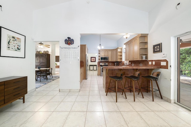 kitchen featuring high vaulted ceiling, decorative light fixtures, and stainless steel appliances