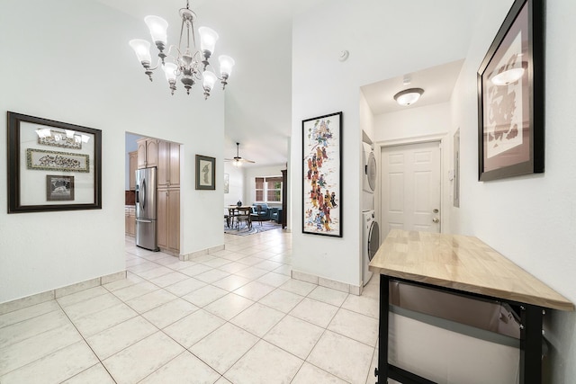 corridor with stacked washer / dryer, a high ceiling, and light tile patterned floors