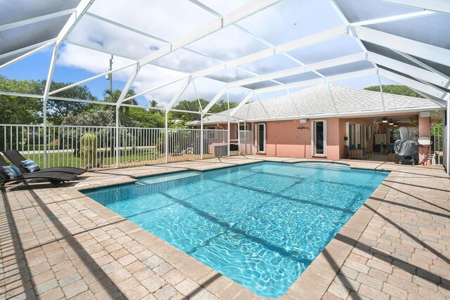 view of swimming pool featuring a patio, ceiling fan, and glass enclosure