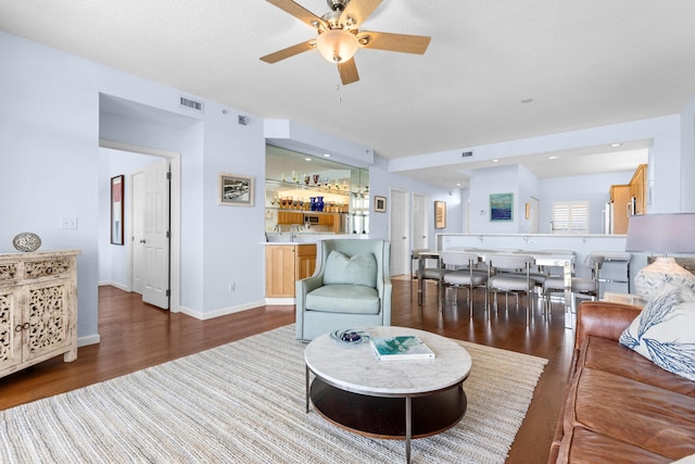 living room with hardwood / wood-style floors, bar area, and ceiling fan