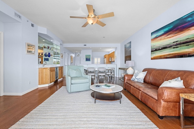 living room with ceiling fan, indoor bar, beverage cooler, and dark hardwood / wood-style flooring