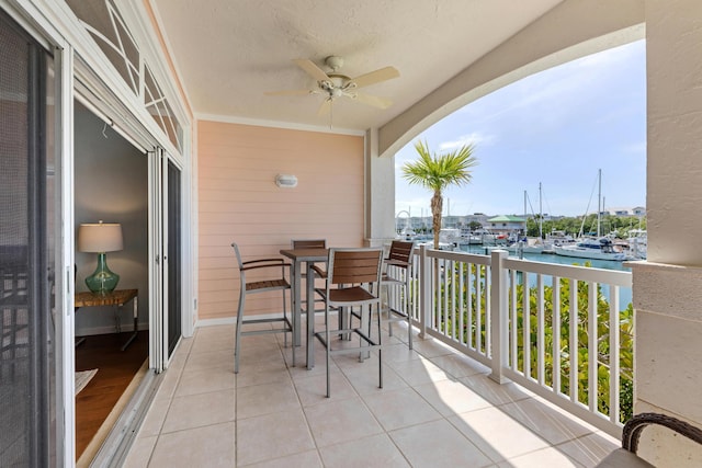 balcony featuring a water view and ceiling fan