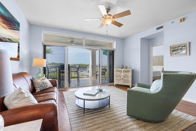 living room featuring ceiling fan, hardwood / wood-style floors, and a textured ceiling