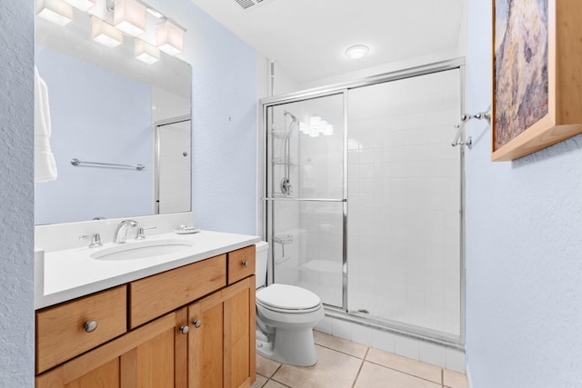 bathroom featuring tile patterned flooring, vanity, a shower with shower door, and toilet