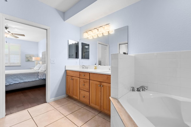 bathroom featuring tile patterned flooring, vanity, a relaxing tiled tub, and ceiling fan