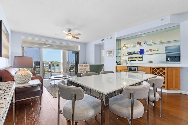 dining area with ceiling fan, a textured ceiling, and dark hardwood / wood-style flooring