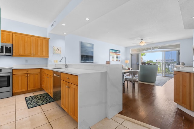 kitchen featuring sink, light tile patterned floors, ceiling fan, appliances with stainless steel finishes, and kitchen peninsula