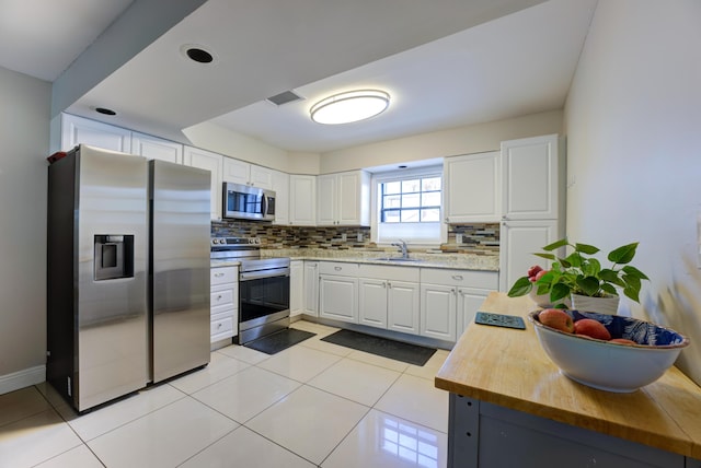 3314 Northside Dr Unit 31, Key West, FL 33040 - kitchen featuring stainless steel appliances, a sink, wooden counters, tasteful backsplash, and white cabinets