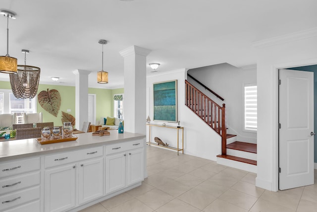 kitchen featuring ornate columns, ornamental molding, decorative light fixtures, and white cabinets