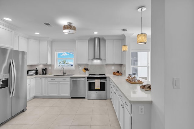 kitchen featuring wall chimney exhaust hood, tasteful backsplash, appliances with stainless steel finishes, pendant lighting, and white cabinets