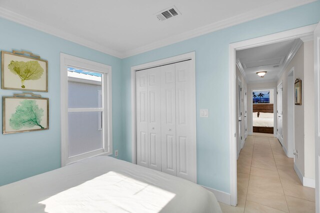 tiled bedroom with crown molding and a closet