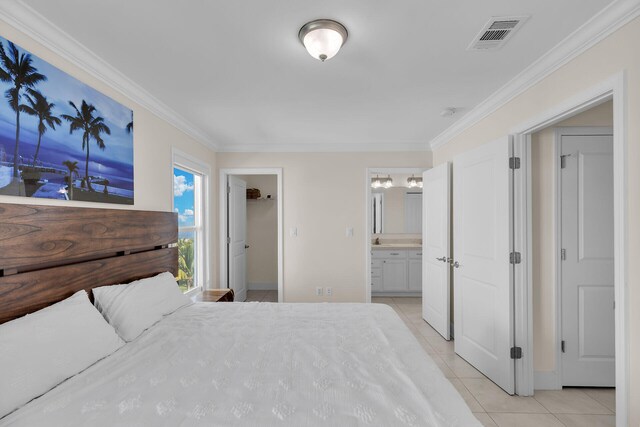 bedroom with connected bathroom, light tile patterned floors, crown molding, and a walk in closet