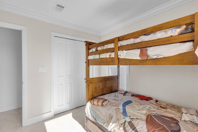 tiled bedroom featuring ornamental molding and a closet