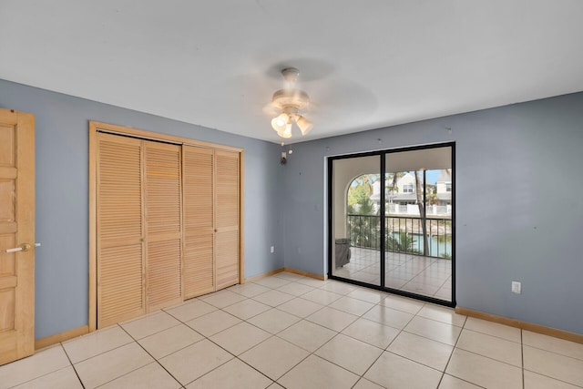 unfurnished bedroom featuring access to exterior, a closet, light tile patterned flooring, and baseboards