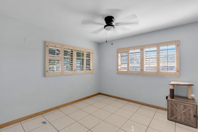 empty room with light tile patterned floors, ceiling fan, and baseboards