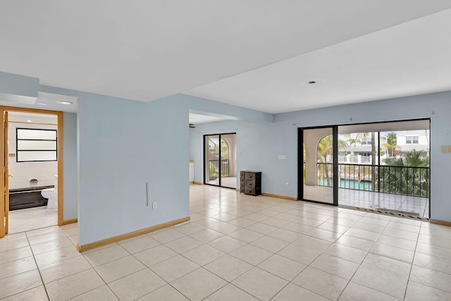 empty room with light tile patterned floors and baseboards